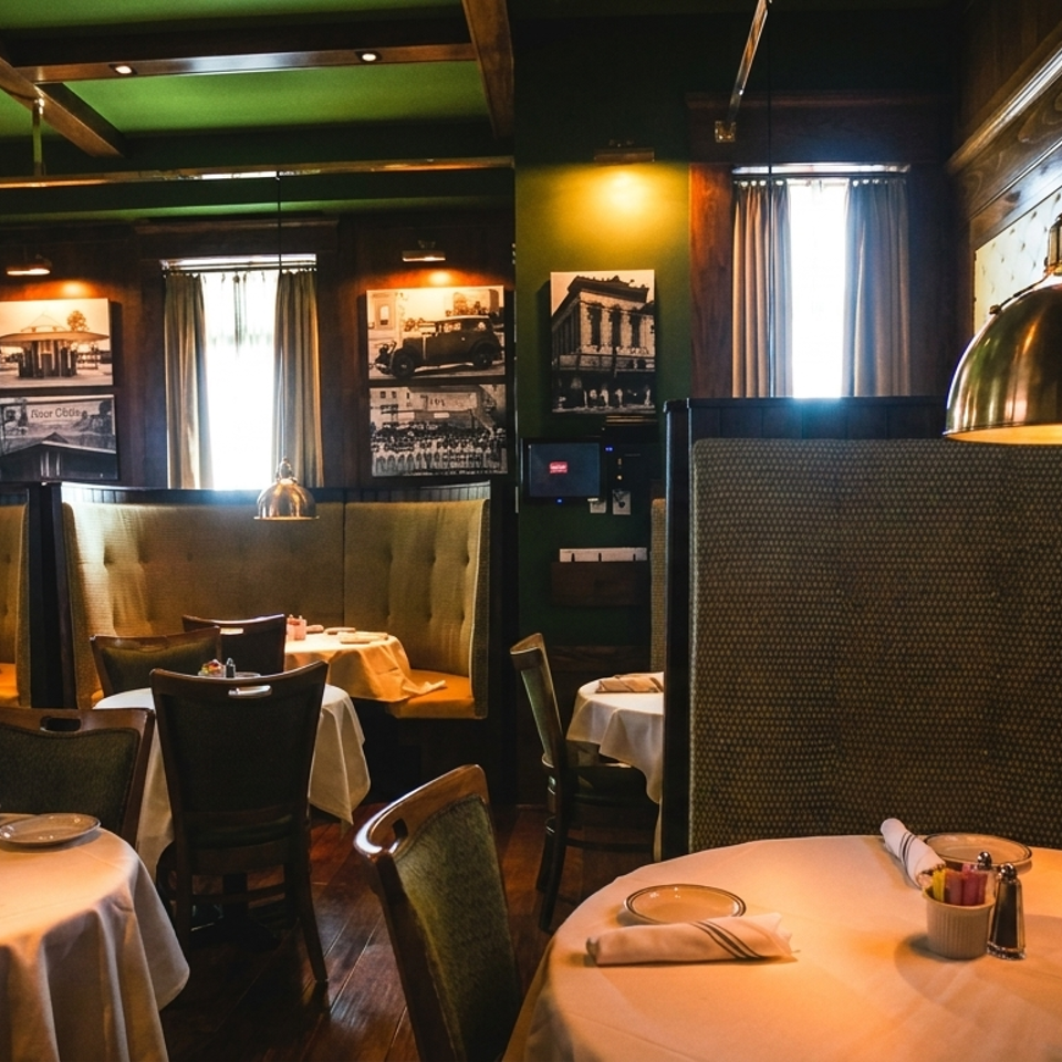Cozy restaurant interior with green walls, dark wood accents, and round tables with white tablecloths.
